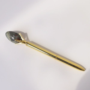 Detail showing creative golden metal ballpoint pen with a natural gemstone top accent