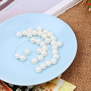 Macro shot of white wrinkled faux pearl beads with holes in a ceramic dish