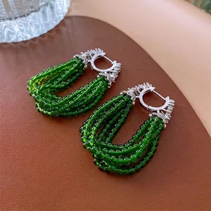 Boucles d'oreilles vintage en perles vert émeraude avec zircons sur fond de cuir marron
