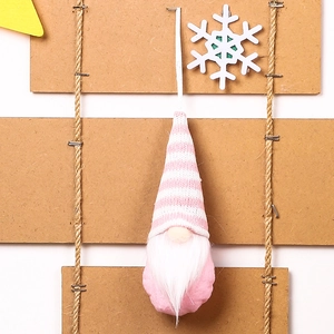 Detailed view of pink knitted Christmas gnome ornament with white beard and hanging string