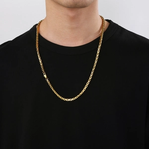 Detail view of a gold square link chain necklace worn by a male model on a black shirt