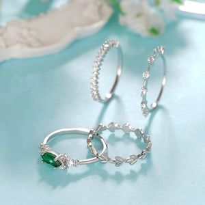 Elegante set de cuatro anillos de plata con gema verde talla marquesa y detalles de hojas
