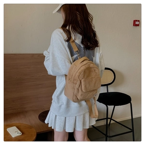Primer plano de una mochila de felpa marrón usada por una modelo en un ambiente acogedor