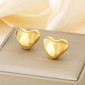 Macro shot of polished 18k gold heart stud earrings on beige satin display