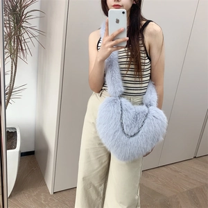Light blue heart-shaped plush crossbody bag with silver chain detail shown in mirror selfie