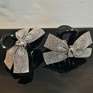 Close-up of sparkling rhinestone bow hair claws with iridescent and white crystals
