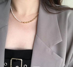 Detailed view of bicolor necklace showing white pearls and gold barrel beads on neck