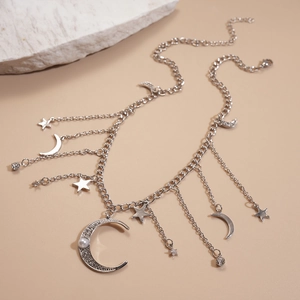 Collier argenté avec pendentif étoile lune, perles et strass sur fond beige doux