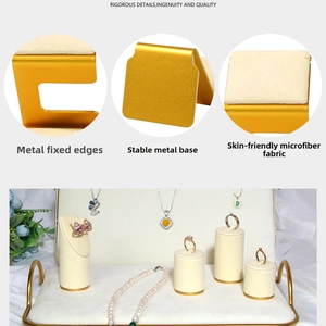 Detail of jewelry display set featuring beige microfiber and gold metal ring stands