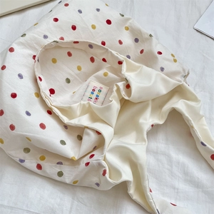 Détail de pois colorés sur tote bag en toile blanche avec étiquette de marque