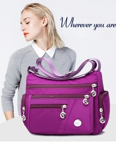 Close-up of purple waterproof nylon crossbody bag with multiple zippered pockets and strap