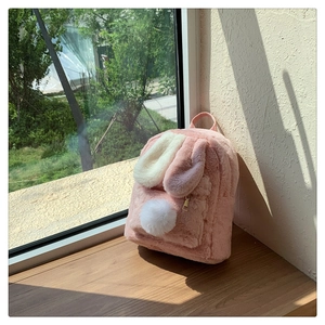 Detail of a pink fuzzy rabbit backpack featuring cute long ears and a white plush tail