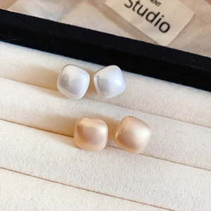 Macro view of square bread pearl earrings in white and champagne on velvet tray