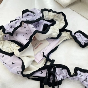 Detailweergave van paarse draagtas met zwarte strikprint en schouderband met ruches