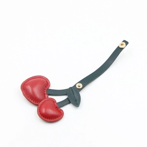 Faux fur cherry keychain with red heart-shaped plush balls and green leaf bag charm