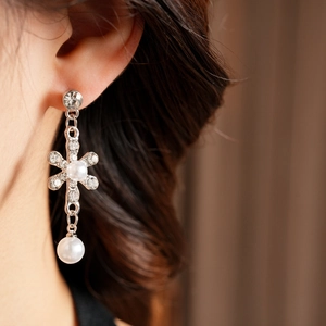 Macro shot of a floral silver earring with shimmering diamonds and white pearls on a model