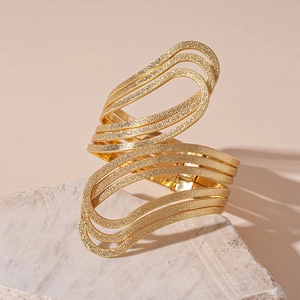 Macro view of multi-layer wavy gold bangle with textured hammered metal finish