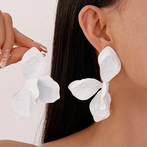 Close-up of white matte flower earrings worn by a model showcasing minimalist petal design