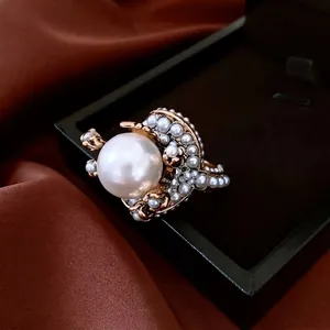Vintage gold flower ring with large central pearl on elegant dark satin background