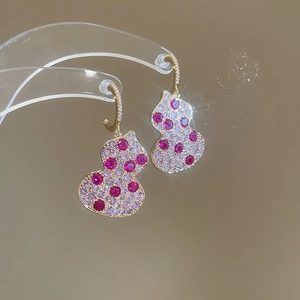 Macro shot of gold earrings with pavé-set red and pink zircon in a gourd design