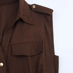 Détail d'un haut sans manches en lin marron foncé avec col pointu et boutons dorés élégants