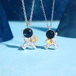 Detailed macro view of astronaut necklaces with blue galaxy helmets and gold accents