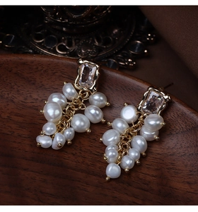 Detail of grape cluster earrings with baroque pearls and rhinestones on a wooden tray