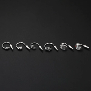 Macro detail of gothic punk piercing set featuring skull, dragon claw, and snake designs