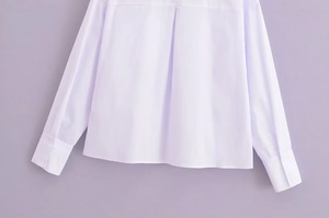 Détails d'une chemise blanche à manches longues avec poignets boutonnés et pli dos