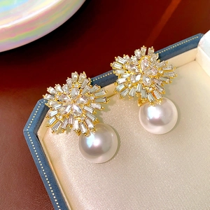Macro shot of gold flower earrings with zircon studs and white pearls in a blue velvet box