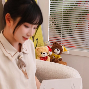 Close-up of Christmas teddy bears in hats and bows placed on a cozy sunlit windowsill