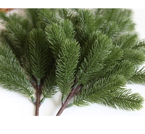 Close-up of realistic green artificial pine branch with detailed needles and wood texture