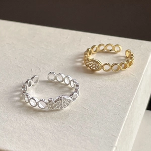 Detail of silver and gold fish rings with zircon inlay and open band design