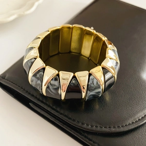 Detailed shot of retro resin marble pattern bracelet with golden metal triangles on black leather