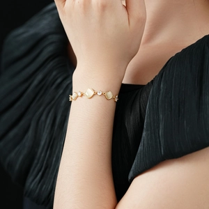 Goldenes Armband mit Katzenaugen-Steinen und Zirkonia am Handgelenk des Models