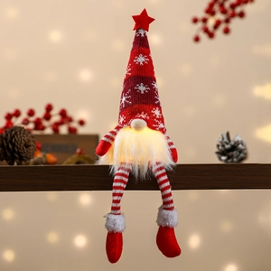 Close-up of a lighted red knitted Christmas gnome with snowflake pattern on wooden board
