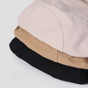 Close-up of stacked cotton sun hats in beige, khaki, and black showing twill texture