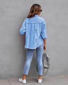 Detail der hellblauen Jeansjacke mit ausgefranstem Saum und Rissen auf der Rückseite