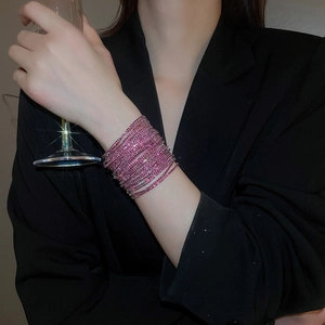 Detailed view of layered pink crystal elastic bracelets on wrist with black blazer background