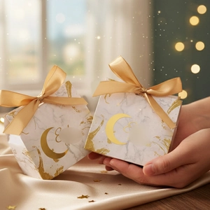 Detail showing marble texture Eid gift box with golden moon and ribbon held in hands
