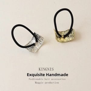Detailed close-up of gold and silver textured alloy hair ties with black elastic bands