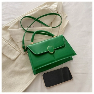 Détail du sac carré en similicuir vert vif avec poignée et finitions métalliques dorées