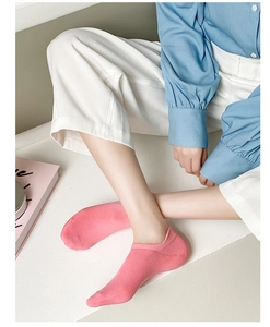 Close-up of pink low-cut cotton socks with tab design worn by model in casual indoor setting