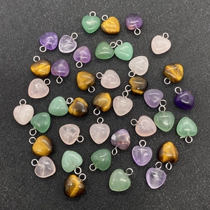 Flat lay of heart-shaped crystal pendants including amethyst and rose quartz on black background