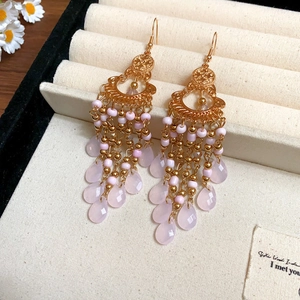 Detail of vintage bohemian gold tassel earrings with pink beads in a jewelry box