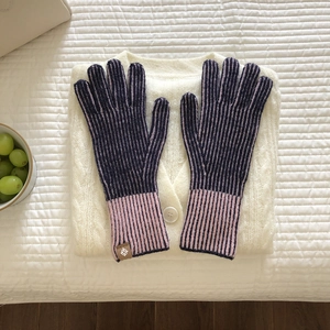 Primer plano de guantes de punto a rayas moradas y rosas sobre textura blanca