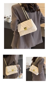 Detail of a beige quilted shoulder bag featuring a gold chain strap and metal lock closure