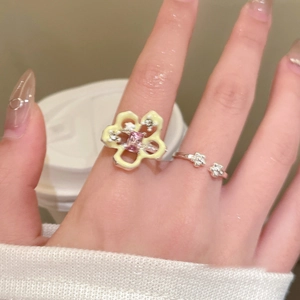 Detailed shot of yellow enamel flower ring and silver band worn on fingers