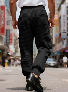 Detail view of black waffle texture cargo pants with multi-pockets and ribbed cuffs