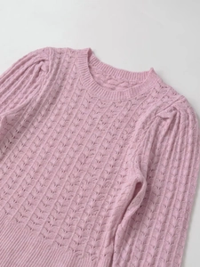 Detail of pink hollow out knit top featuring ribbed cuffs and crew neck texture